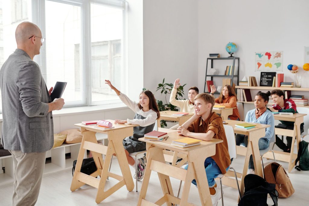 IELTS Speaking Part 2 education cue cards: students raising their hands in a classroom