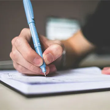 ielts writing test, a guy writing a letter with pen and paper